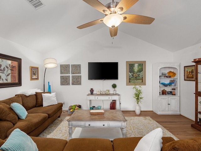 living area featuring wood finished floors, visible vents, baseboards, vaulted ceiling, and a ceiling fan