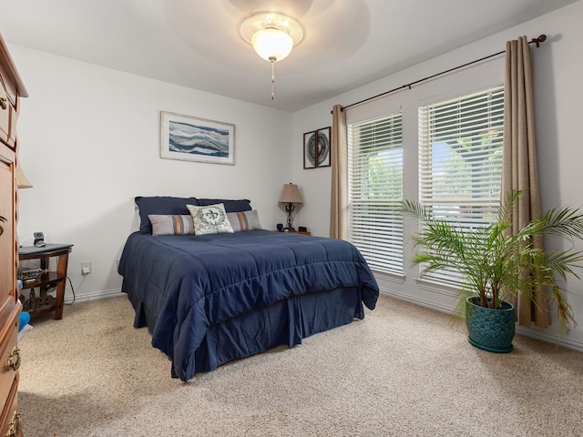 bedroom with light carpet, a ceiling fan, and baseboards