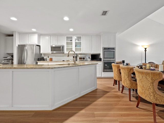 kitchen featuring appliances with stainless steel finishes, light wood-style floors, white cabinetry, a sink, and recessed lighting