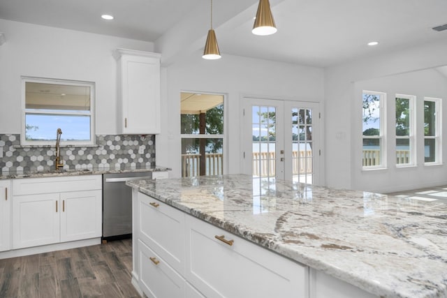 kitchen with tasteful backsplash, stainless steel dishwasher, hanging light fixtures, sink, and dark wood-type flooring