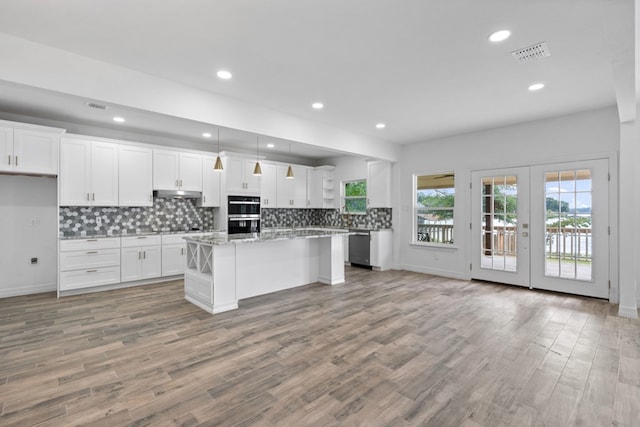 kitchen featuring light hardwood / wood-style flooring, decorative backsplash, a kitchen island, and white cabinetry