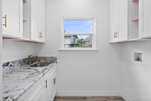 kitchen with light stone counters, sink, hardwood / wood-style floors, and white cabinetry