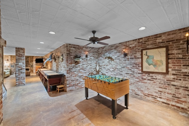 recreation room featuring ceiling fan, brick wall, and decorative columns