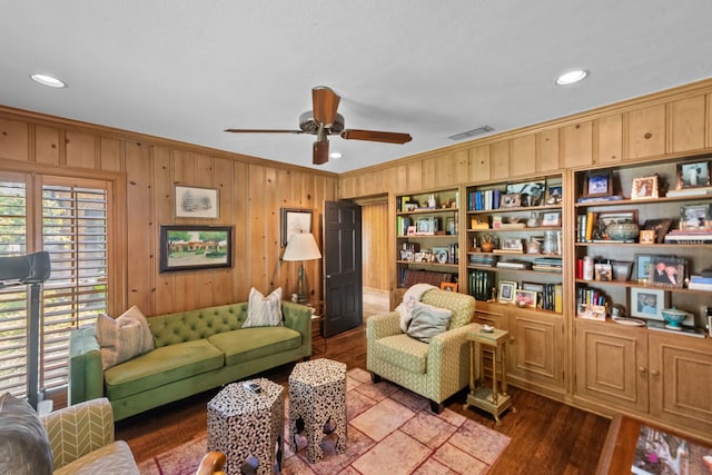 living room featuring ceiling fan, wood walls, wood-type flooring, and crown molding