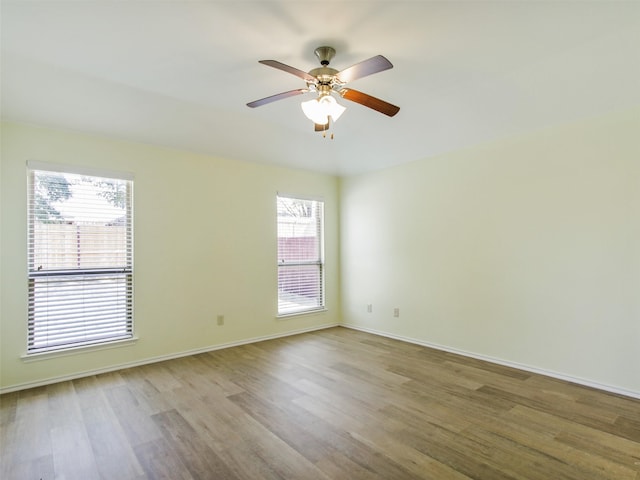 spare room with ceiling fan, a wealth of natural light, and light hardwood / wood-style floors