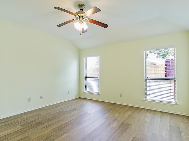 empty room featuring ceiling fan, lofted ceiling, plenty of natural light, and hardwood / wood-style floors