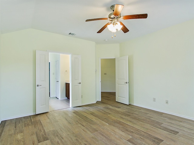 unfurnished bedroom featuring ceiling fan, light hardwood / wood-style flooring, ensuite bathroom, and vaulted ceiling