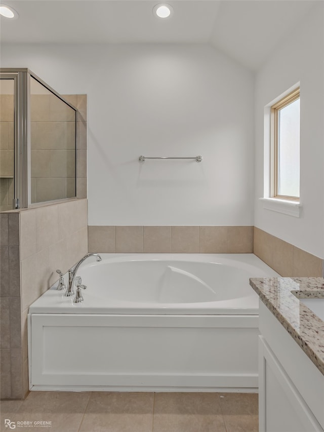 bathroom featuring lofted ceiling, vanity, tile patterned floors, and a tub