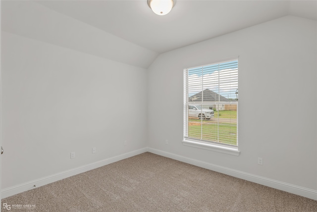 carpeted spare room with a wealth of natural light and vaulted ceiling