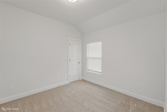 spare room featuring light colored carpet and lofted ceiling