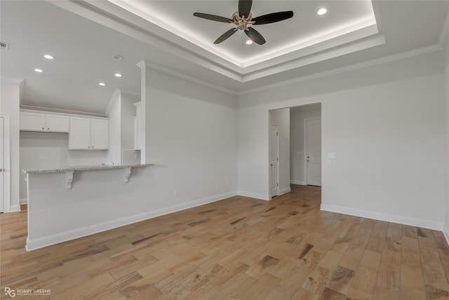 interior space featuring ornamental molding, a tray ceiling, light hardwood / wood-style floors, and ceiling fan