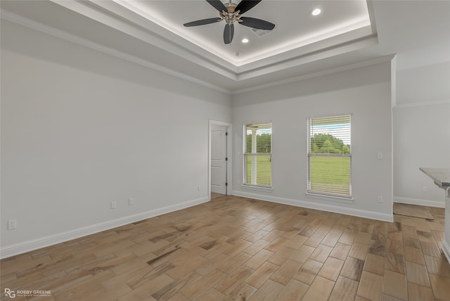 spare room with light wood-type flooring, crown molding, a tray ceiling, and ceiling fan