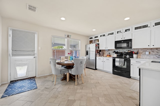 kitchen with white cabinetry, sink, black appliances, light stone countertops, and decorative backsplash