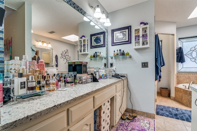 bathroom with a textured ceiling, tile patterned flooring, vanity, and a relaxing tiled tub