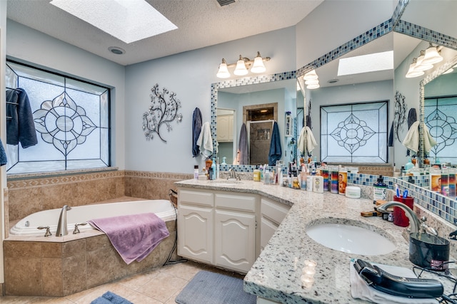 bathroom featuring vanity, a skylight, a textured ceiling, plus walk in shower, and tile patterned floors