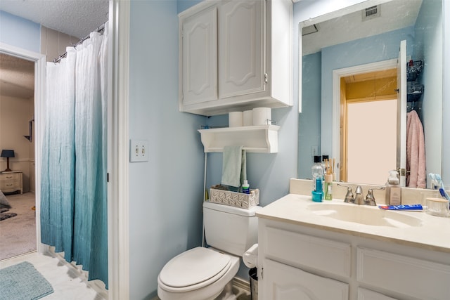 bathroom with a textured ceiling, vanity, and toilet