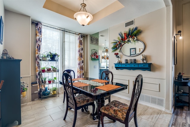 dining space featuring light wood-type flooring and a tray ceiling