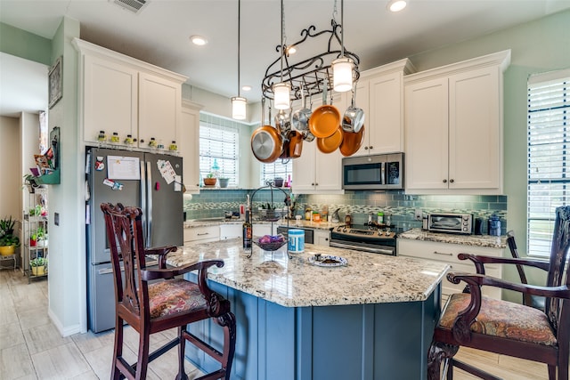 kitchen with stainless steel appliances, a center island, hanging light fixtures, and a healthy amount of sunlight