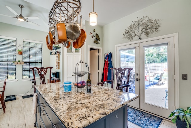 kitchen featuring light tile patterned floors, decorative light fixtures, light stone countertops, ceiling fan, and french doors