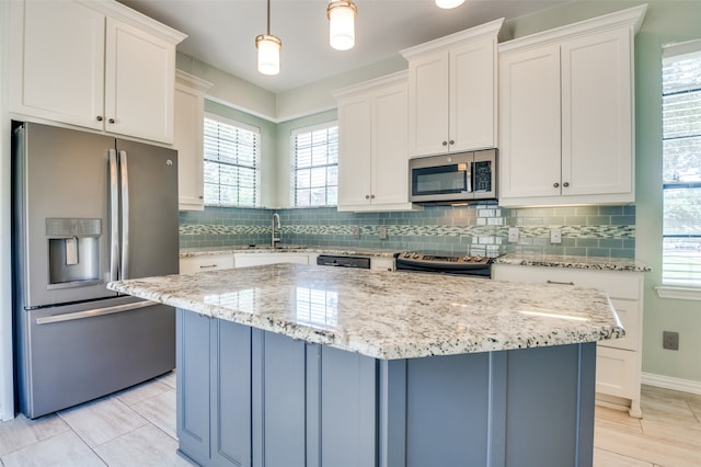 kitchen with a center island, appliances with stainless steel finishes, hanging light fixtures, and white cabinetry