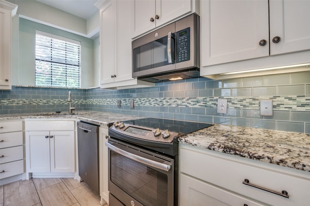 kitchen with light stone counters, stainless steel appliances, backsplash, and white cabinetry