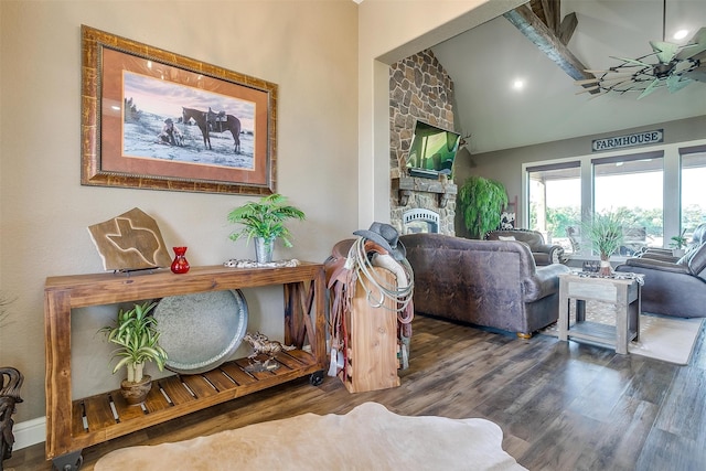 living room featuring ceiling fan, dark hardwood / wood-style floors, high vaulted ceiling, and a stone fireplace