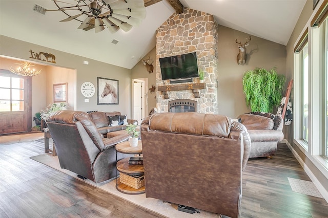 living room featuring high vaulted ceiling, wood-type flooring, ceiling fan with notable chandelier, a fireplace, and beam ceiling