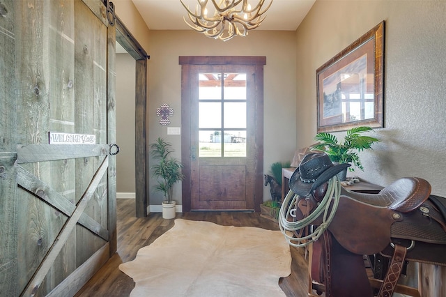 doorway to outside featuring a notable chandelier, a barn door, and dark hardwood / wood-style flooring