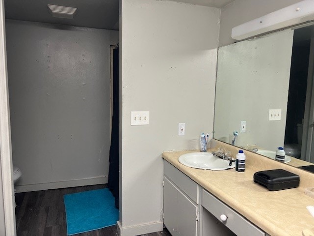 bathroom with wood-type flooring, vanity, and toilet