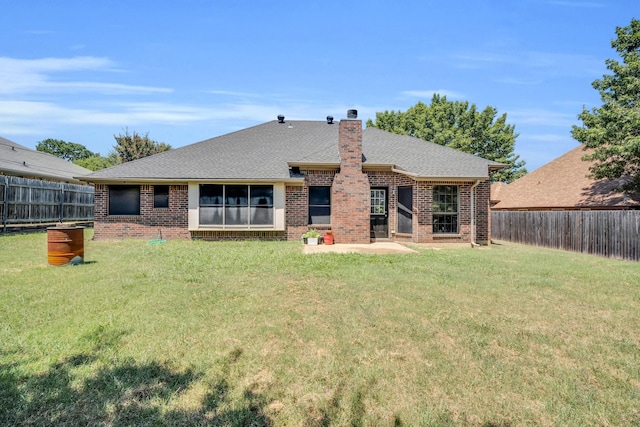 back of house featuring brick siding, a yard, a chimney, a shingled roof, and a fenced backyard