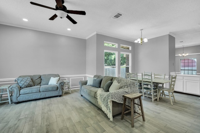 living area with visible vents, wainscoting, light wood-style flooring, ornamental molding, and a textured ceiling