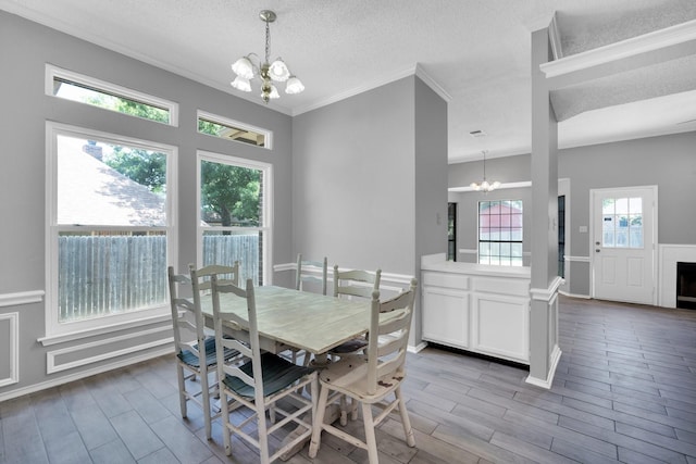 dining space featuring an inviting chandelier, wood tiled floor, a textured ceiling, and crown molding