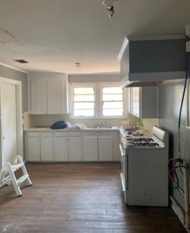 kitchen featuring white cabinets, light wood-type flooring, white gas stove, and ornamental molding