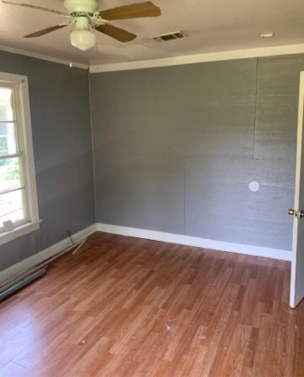 unfurnished room featuring hardwood / wood-style floors, ornamental molding, a wealth of natural light, and ceiling fan