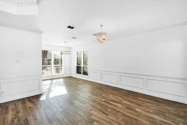 spare room featuring dark hardwood / wood-style flooring, ornamental molding, and an inviting chandelier