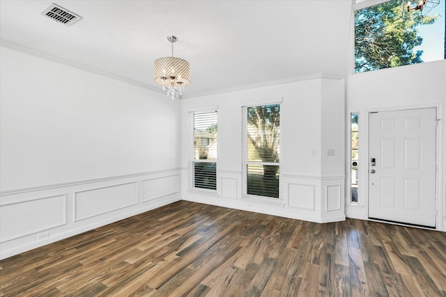 foyer featuring dark hardwood / wood-style flooring, ornamental molding, and a chandelier