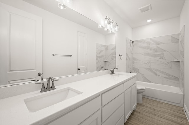 full bathroom featuring toilet, tiled shower / bath, and vanity