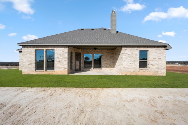 rear view of property with ceiling fan, a lawn, and a patio