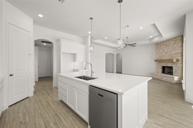 kitchen featuring ceiling fan, dishwasher, sink, a tray ceiling, and a kitchen island with sink