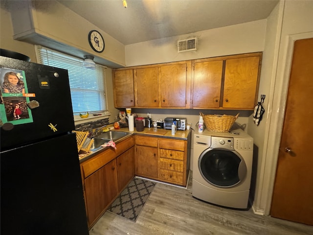 clothes washing area with washer / clothes dryer, cabinets, light wood-type flooring, and sink