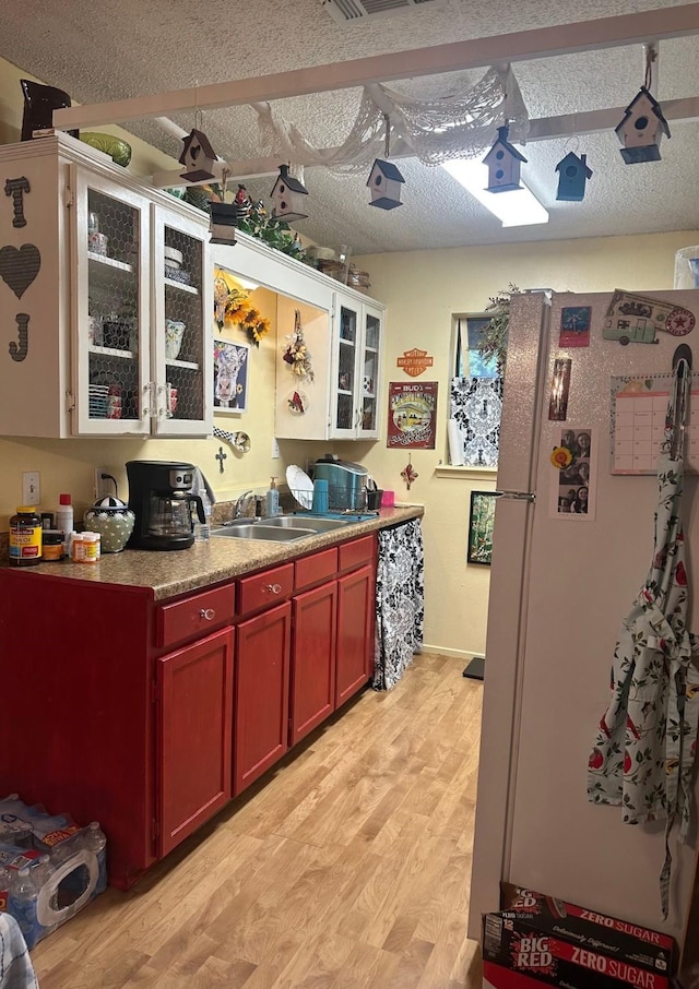 kitchen featuring a textured ceiling, light countertops, light wood-type flooring, and freestanding refrigerator