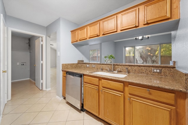 kitchen featuring light tile patterned flooring, sink, dishwasher, and light stone countertops