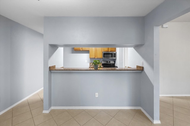 kitchen with kitchen peninsula, stove, and light tile patterned floors