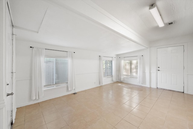 spare room featuring beam ceiling and light tile patterned floors