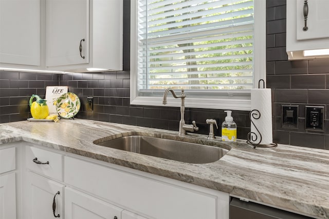 kitchen featuring sink, tasteful backsplash, white cabinetry, and light stone counters