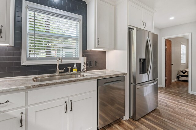 kitchen featuring hardwood / wood-style flooring, tasteful backsplash, appliances with stainless steel finishes, and a healthy amount of sunlight