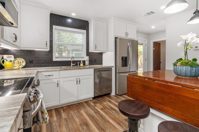 kitchen featuring hardwood / wood-style floors, stainless steel appliances, tasteful backsplash, and a healthy amount of sunlight