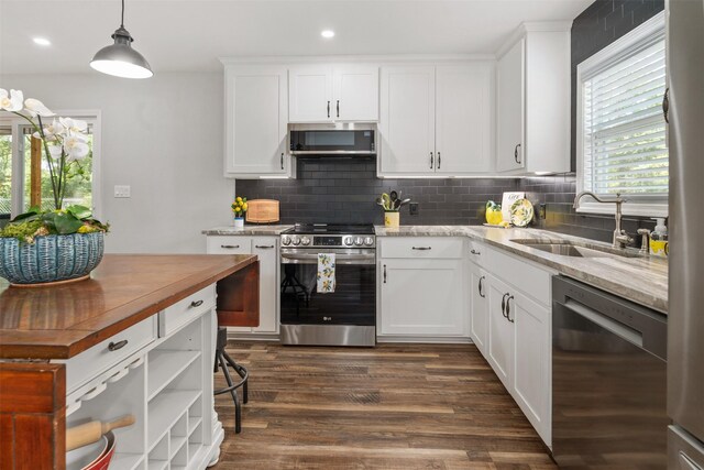 kitchen with backsplash, stainless steel appliances, sink, pendant lighting, and dark wood-type flooring