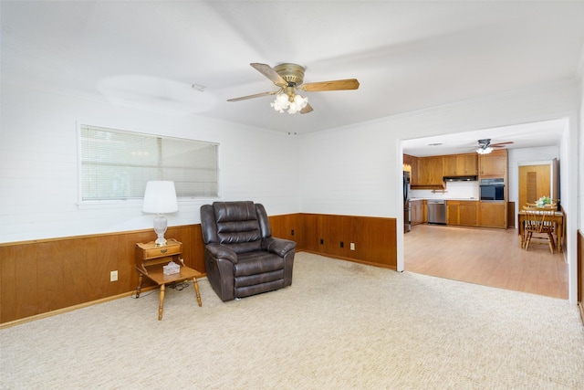 carpeted living room with ceiling fan, crown molding, a fireplace, and wooden walls