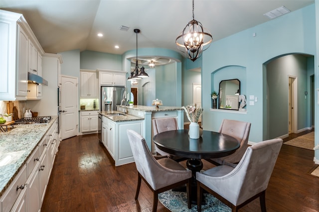 kitchen featuring a center island with sink, appliances with stainless steel finishes, hanging light fixtures, white cabinets, and dark wood-type flooring